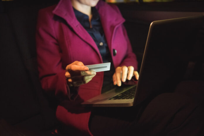 Businesswoman doing online shopping on laptop with credit card in car
